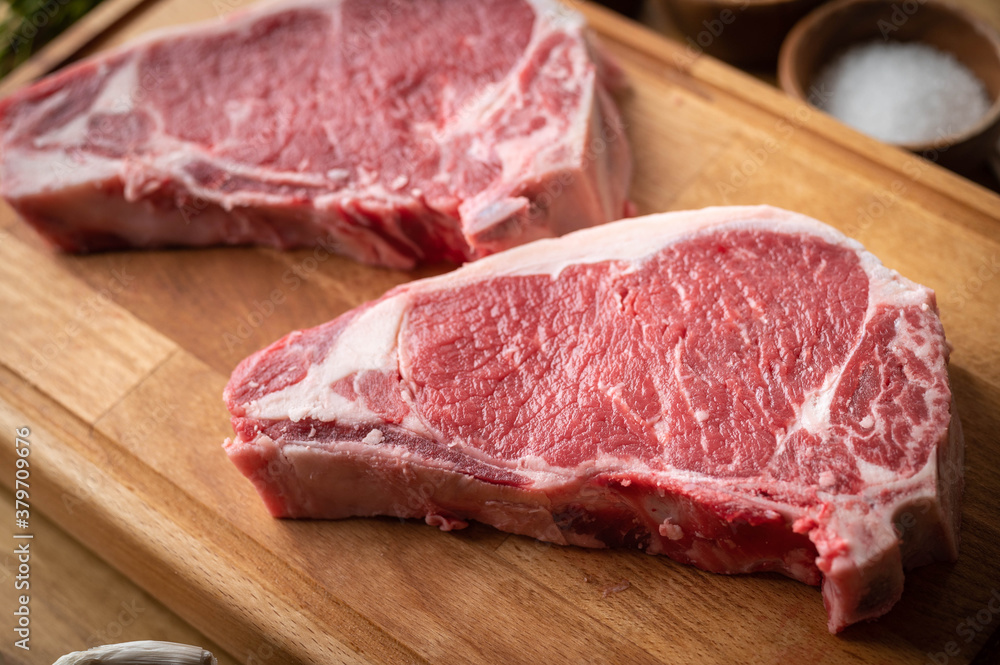 raw steak meat on cutting board in bright kitchen - obrazy, fototapety, plakaty 
