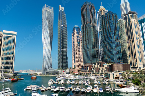 Photography Stunning panoramic view of Dubai Marina skyline, yachts and boats moored at the pier on a bright sunny day