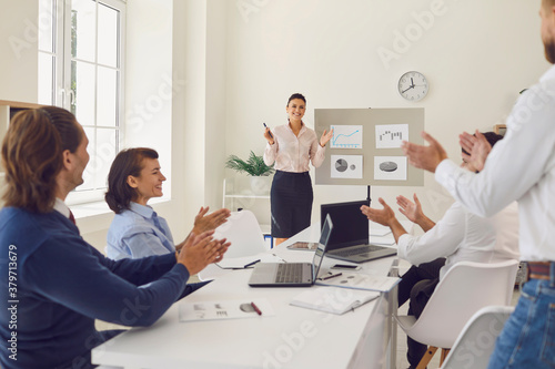 Happy employees celebrating sales increase in corporate meeting with sales manager