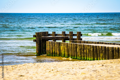 Beautiful pop sea waves, beach and wooden pier, breakwater