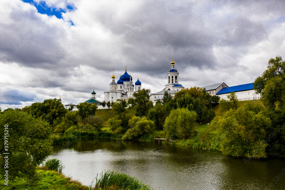 a panoramic view of the old monastery of white stone with blue domes against the background of blue clouds filmed from a drone