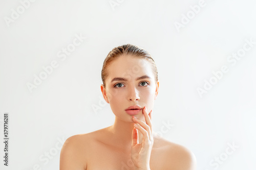 Lip augmentation. Aesthetic cosmetology. Portrait of sensual woman with perfect skin nude makeup bare shoulders looking at camera isolated on light white empty space background. Face contouring.