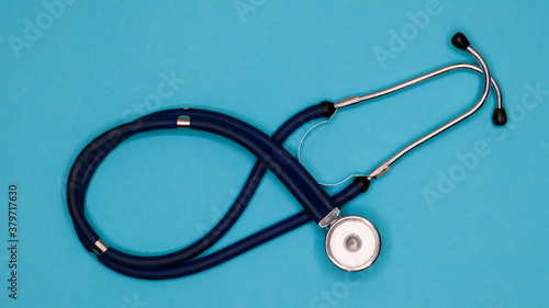 Old shabby stethoscope on a blue background.