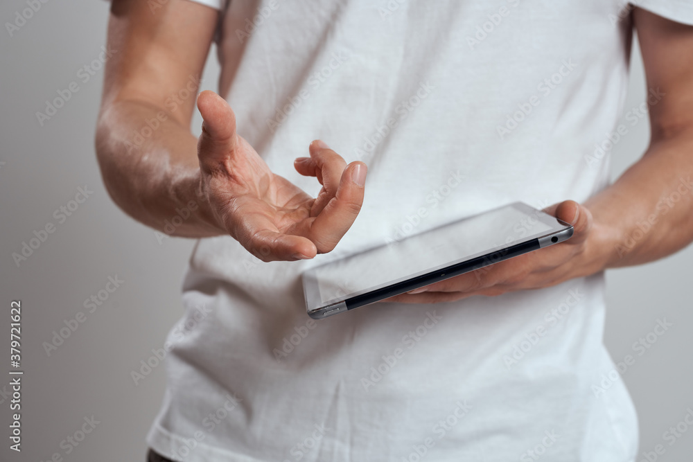 Tablet with a touch screen on a light background male hands white t-shirt cropped view Tablet with a touch screen on a light background male hands white t-shirt cropped view