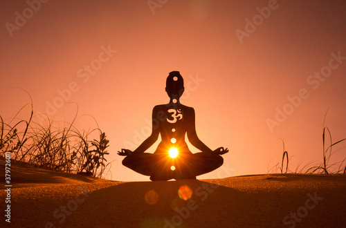 Silhouette of a person doing yoga with the root chakra symbol photo