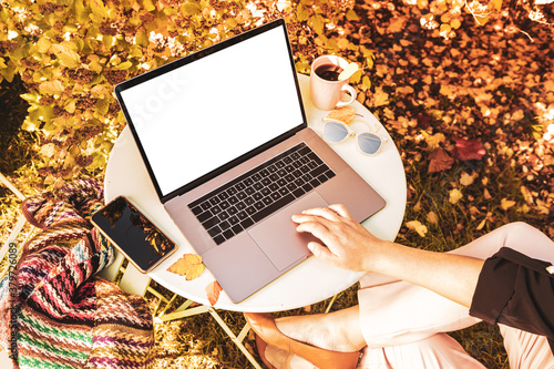 Woman working on the laptop computer in the autumn (fall) garden