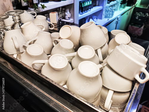 Pile of white porcelain coffee and tea cups on the bar. Equipment for the restaurant business.