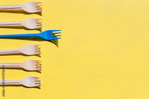 Organic bamboo disposable cutlery vs plastic ones on yellow background. Environmentally friendly wooden and non-oragnic plastic forks.ecology, zero waste concept. copyspace.
