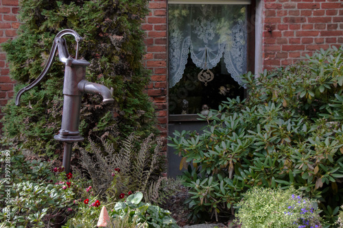 Wasserpumpe vor altem Haus