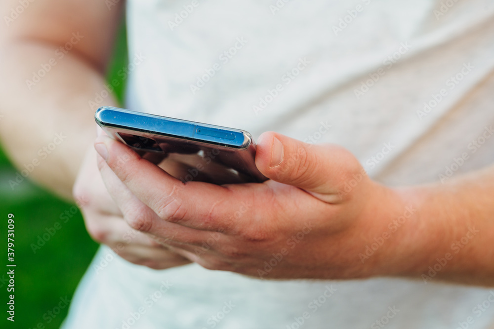 close-up shot of male hands holding smartphone with blank screen copy space for your text message or information content, against green nature background close-up shot of male hands holding smartphone with blank screen copy space for your text message or information content, against green nature background