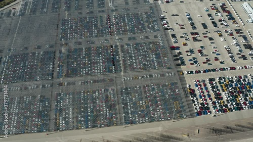 Aerial video of stock car parking. Flying over big industrial zone with big parking lot of brand new cars. Many cars waiting for sale and transportation. Automobile industry.
