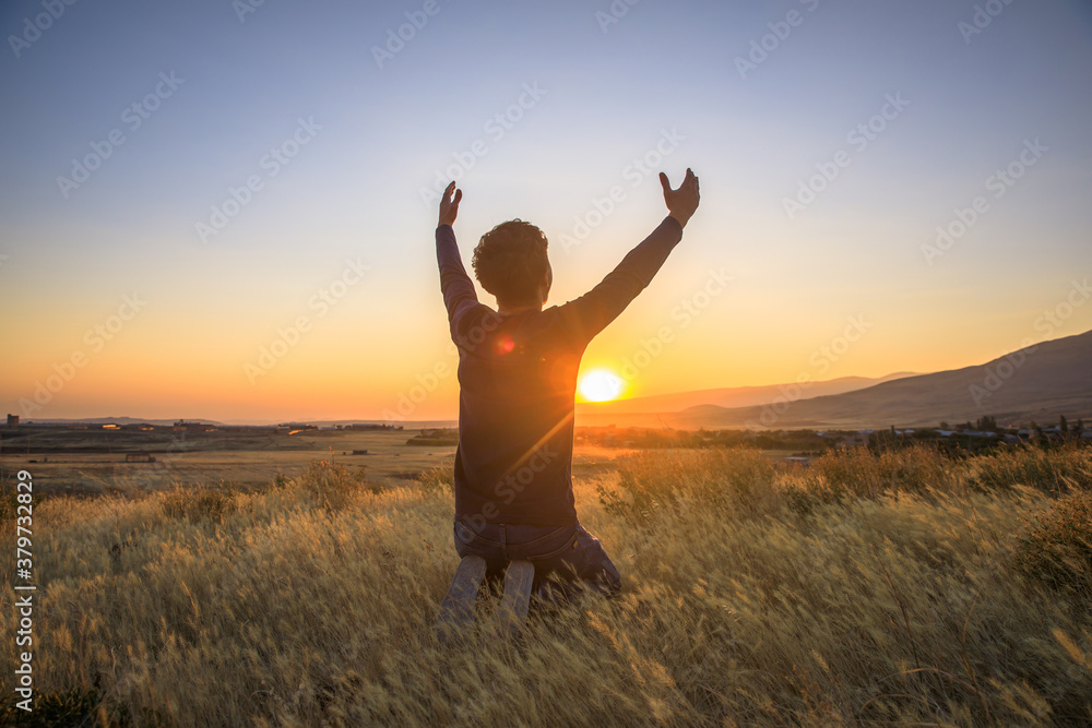 man praying at the sunset - obrazy, fototapety, plakaty 
