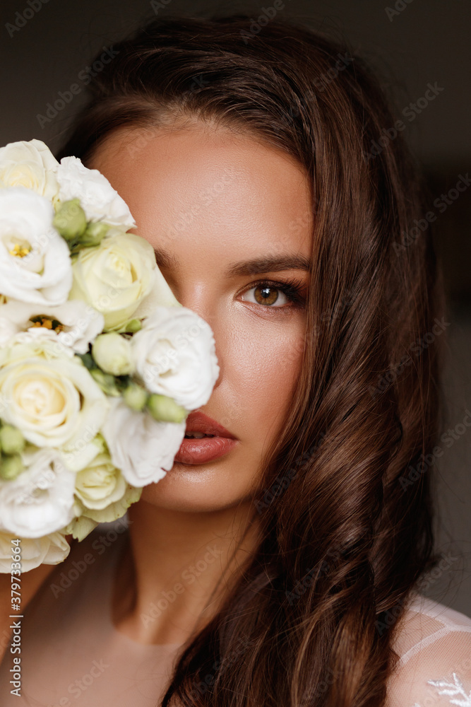 the bride covers her face with a bouquet. Wedding make-up
