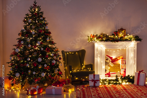 Christmas tree with gifts fireplace lights garlands at night on New Year's Eve in the interior of the room