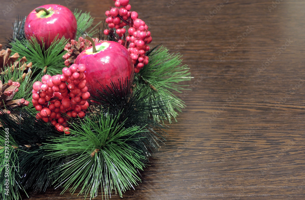 Background with a Christmas wreath with red berries, apples and pine cones on the surface with space for text.