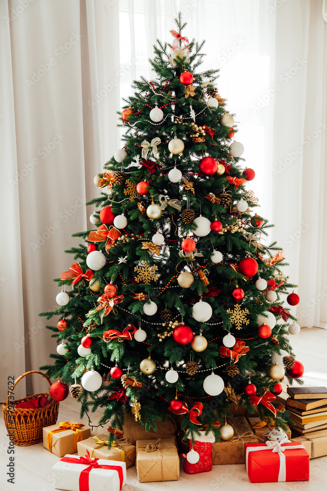 Christmas tree with gifts of garland lights for the new year in the interior of the white room as a backdrop