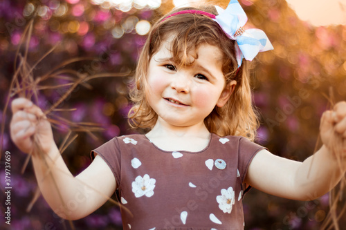 Menina loira, criança pequena, brincando em meio a um jardim de azaleias, marcando o início da primavera. Menina sorrindo, criança feliz