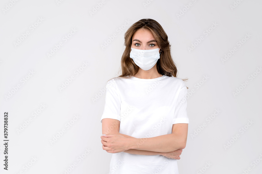 Studio portrait of a young woman wearing a face mask, looking at camera, close up, isolated on white background. Flu epidemic, dust allergy, protection against virus