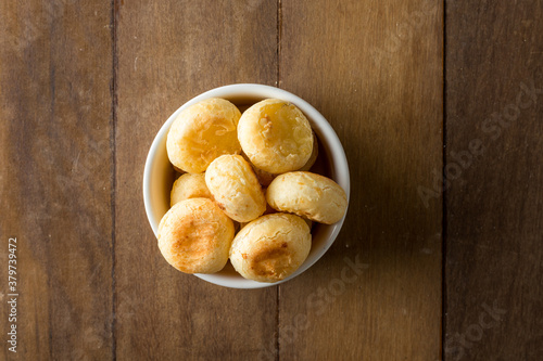 Traditional Brazilian Snack Cheese Bread in a white pot. On a wooden table background. copy space