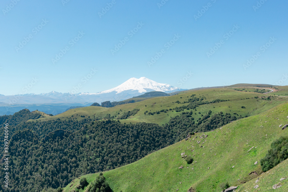Scenic view of the highest peak in Europe, mount Elbrus with green hills on a Sunny summer day.