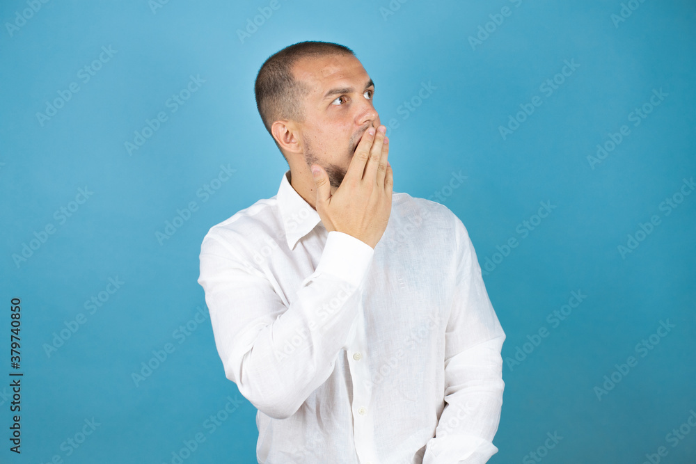 Russian business man wearing white shirt standing over blue background afraid and shocked with surprise expression, fear and excited face.