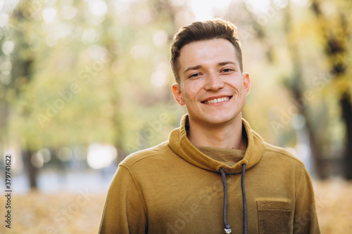Portrait of handsome guy smiling in the autumn park