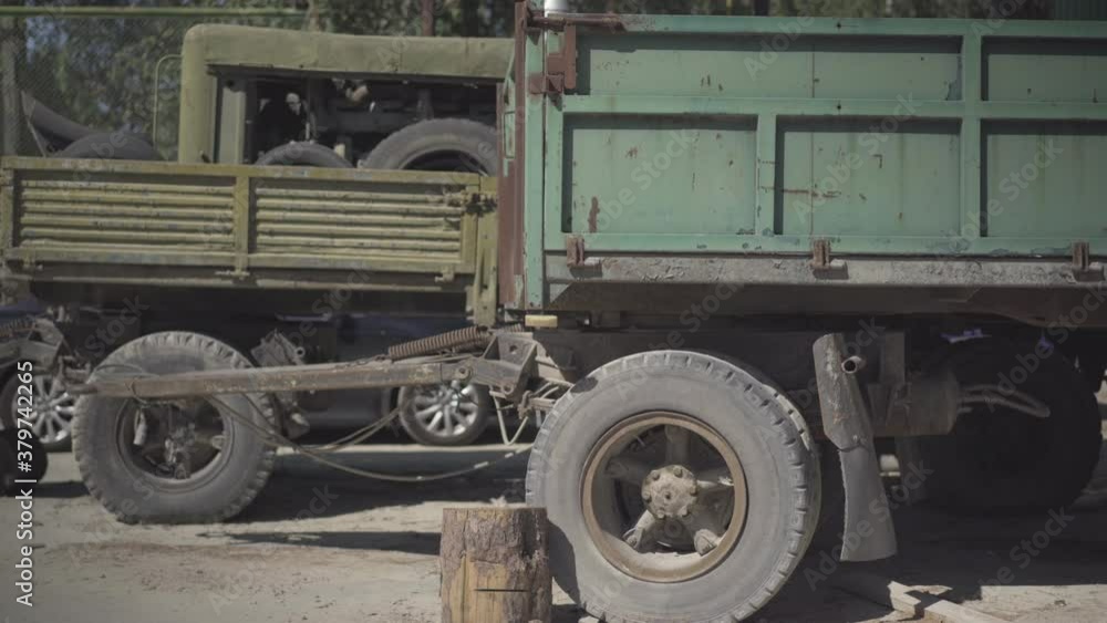 Side view of abandoned rusty machinery on neglected manufacturing site. Old transport standing outdoors under sunlight.