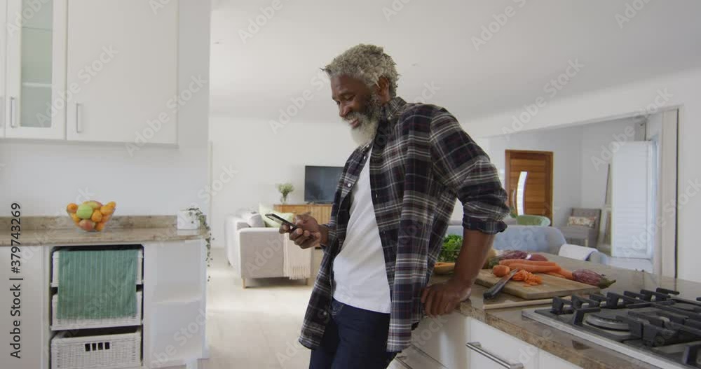 Senior man using smartphone in the kitchen Senior man using smartphone in the kitchen