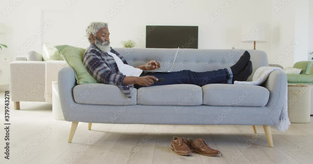 Senior man talking on smartphone while using laptop at home Senior man talking on smartphone while using laptop at home