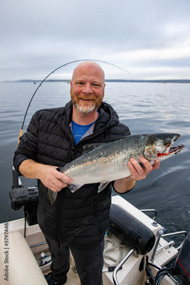 Man holds fresh caught wild Coho Salmon fish Man holds fresh caught wild Coho Salmon fish