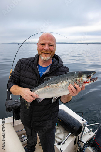 Man holds fresh caught wild Coho Salmon fish