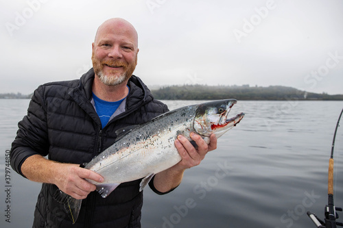 Man holds fresh caught wild Coho Salmon fish