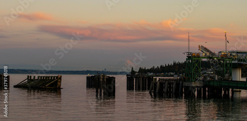 General view of Kingston, Washington ferry dock over the Puget Sound with Mount Rainier under the sunset with a pink and orange colorful sky © Mat Hayward