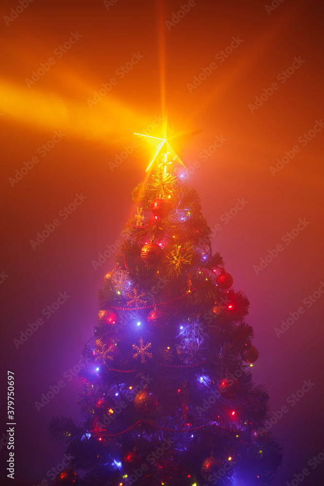 Christmas tree with festive lights, orange background with mist Christmas tree with festive lights, orange background with mist
