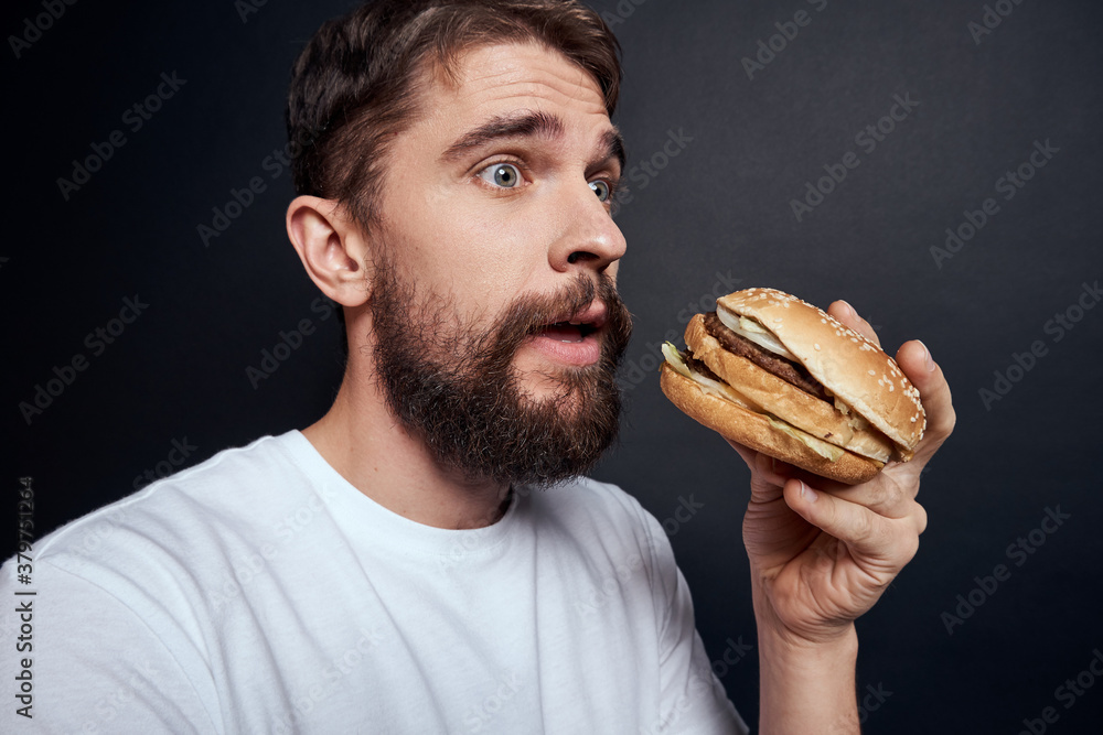 Man eating hamburger fast food restaurant Gourmet eating dark background Man eating hamburger fast food restaurant Gourmet eating dark background