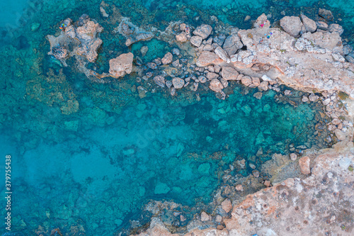 Fototapeta Naklejka Na Ścianę i Meble -  An aerial view of the beautiful Mediterranean Sea, where you can see the cracked rocky textured underwater corals and the clean turquoise water of Protaras, Cyprus,
