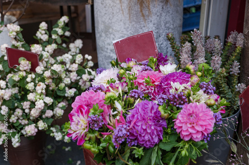 Selected focus view at purple  pink and white bouquet of blooming flowers in front of floral shop in outdoor market in Europe. Typical atmosphere of flower store.   
