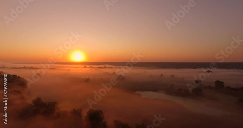 Aerial view of pink sunrise on misty valley of Siverskyi Donets river near Zmiiv city, Ukraine. Forward camera movement photo