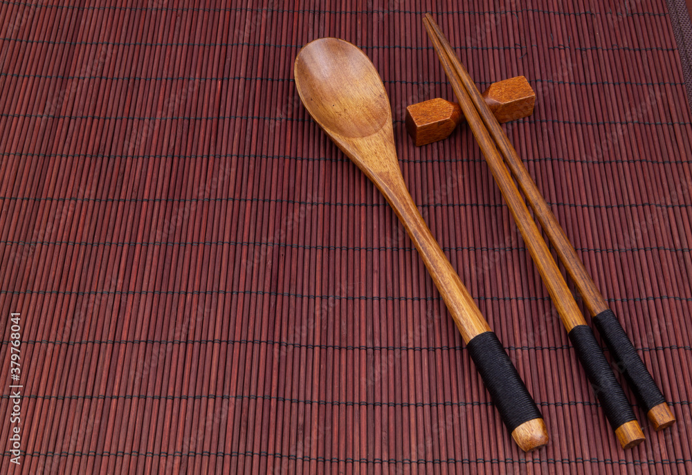 Wooden chopsticks and spoon on bamboo place mat with copy space Wooden chopsticks and spoon on bamboo place mat with copy space