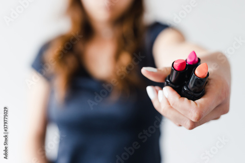 girl holding lipsticks in front of the camera showing the product, beauty bloggers and influencers reviews or tutorials