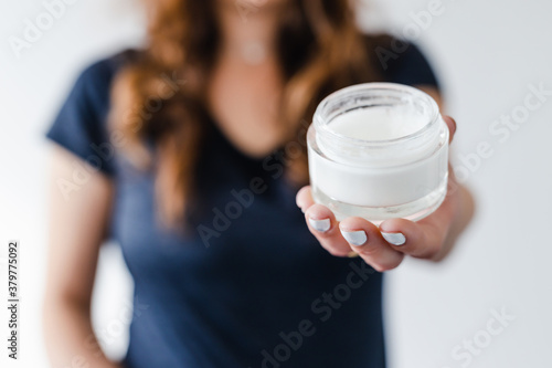 girl holding moisturizer jar in front of the camera showing the product, beauty bloggers and influencers reviews or tutorials