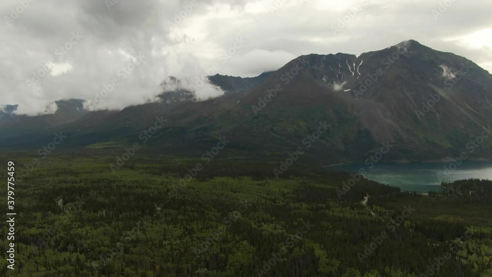 View of Scenic Lake surrounded by Forest and Mountains in Canadian Nature. Aerial Drone Shot. Yukon, Canada. 4K View of Scenic Lake surrounded by Forest and Mountains in Canadian Nature. Aerial Drone Shot. Yukon, Canada. 4K