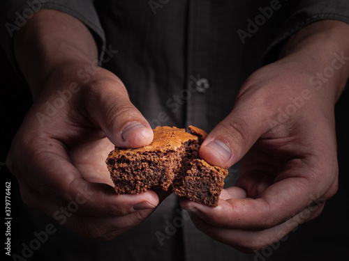 A man breaks a piece of brownie cookies.
