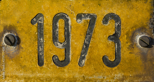 Gelbes verwittertes Schild mit Jahreszahl 1973