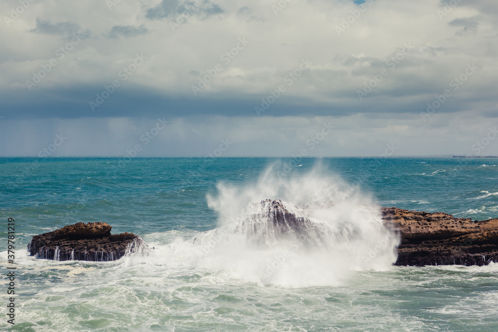 Water splashing against a rock in the ocean on a stormy summer day