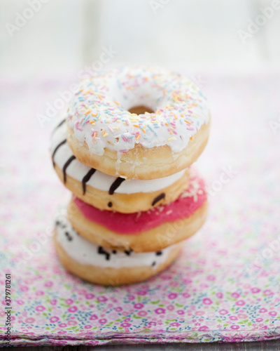 Four different flavored doughnuts on flowered cotton cloth on wooden table photo