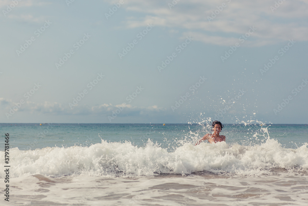 Boy swimming in the ocean playing in the waves Boy swimming in the ocean playing in the waves