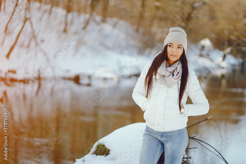 young and stylish girl snadning in a winter snowy park neaw water photo