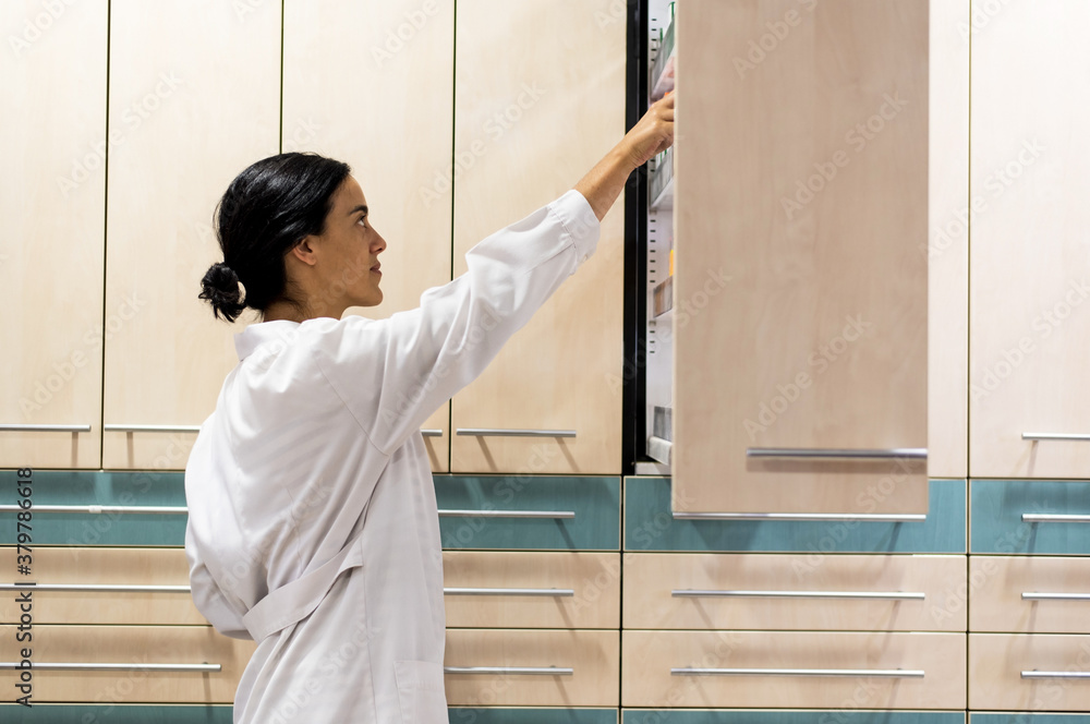 Woman pharmacist tidying some medicaments in a pharmacy Woman pharmacist tidying some medicaments in a pharmacy