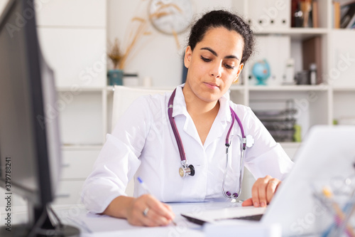 Wallpaper Mural Portrait of female doctor who is working with laptop and documents Torontodigital.ca